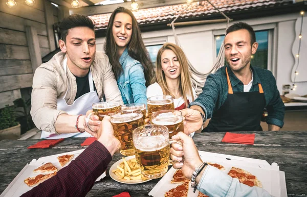 Punto de vista de los jóvenes amigos comiendo pizza para llevar en el patio de casa después del trabajo - Concepto de amistad con gente feliz disfrutando del tiempo juntos y divirtiéndose bebiendo pintas de cerveza - Centrarse en vasos de cerveza —  Fotos de Stock