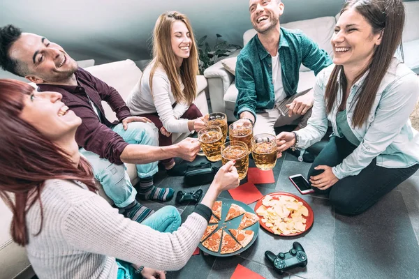 Teman-teman muda makan pizza di rumah setelah kuliah - Konsep persahabatan dengan siswa sekamar menikmati waktu bersama-sama bersenang-senang di apartemen bersama dengan perangkat teknologi dan pengendali video game — Stok Foto