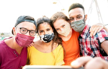 Çok kültürlü milenyum yolcuları kapalı yüz maskeleriyle selfie çekiyorlar - Dönme dolapta güvenli bir şekilde eğlenen gençlerle yeni normal seyahat konsepti - Parlak sıcak güneş ışığı filtresi