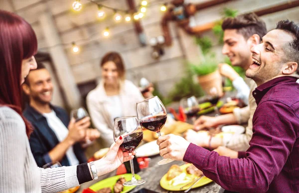 プライベートディナーパーティーでバルコニーで赤ワインを楽しむ幸せな友人 若い人たちが一緒にファッションレストランでバーベキュー料理を食べる 暖かいフィルターでのダイニングライフスタイルのコンセプト メガネに焦点を当てる — ストック写真