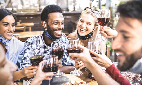 stock image Friends toasting red wine at outdoor restaurant bar with open face mask - New normal lifestyle concept with happy people having fun together on warm filter - Focus on afroamerican guy