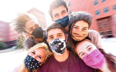 Yüz maskeleriyle selfie çeken çok ırklı arkadaşlar - Üniversite açıldıktan sonra genç öğrencilerle birlikte eğlenen mutlu arkadaşlık konsepti - Radyal çözünürlüklü parlak marsala filtresi