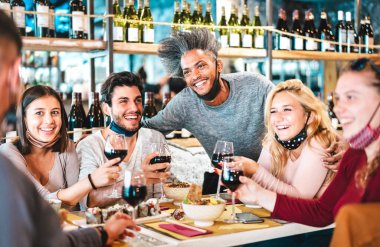 Suşi bar restoranında kırmızı şarap içen arkadaşlar açık maskeli yeni normal yaşam tarzı konsepti, mutlu insanların canlı filtrede birlikte eğlenmesi, Afroamerikalı adama odaklan.
