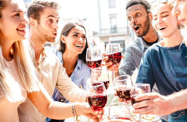 ランチパーティーで赤ワインを飲みながら楽しむ幸せな多人種間の友人 レストランワイナリーでバーベキュー食品を一緒に食べる若者 明るい暖かいフィルターでのダイニングライフスタイルのコンセプト — ストック写真