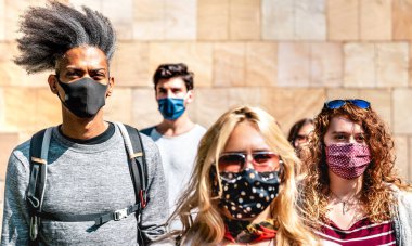 Kentsel bağlamda duvarın yanında yürüyen çok ırklı kalabalık - Korumacı yüz maskesi takmış gençlerin olduğu yeni normal yaşam tarzı konsepti - sol Afrikalı Amerikalı adam üzerine seçici odaklanma
