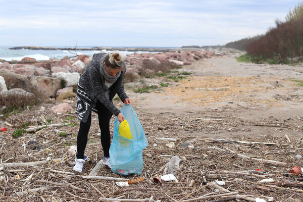 Молодая девушка забирает мусор с пляжа
.