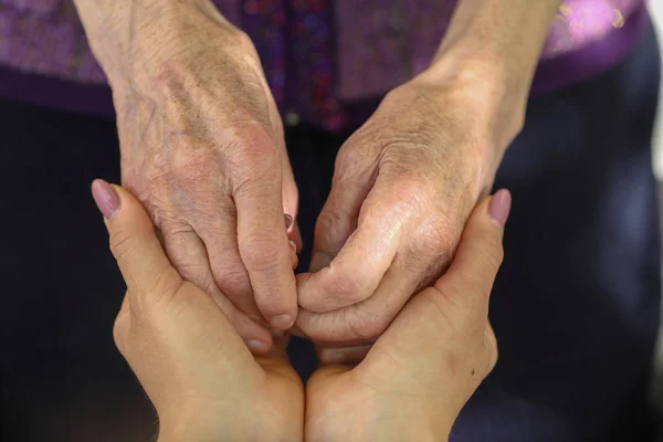 Руки молодых взрослых и пожилых женщин. Старшие и молодые держатся за руки снаружи. Концепция пожилых людей — стоковое фото