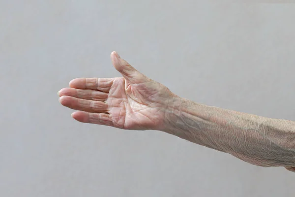 Το χέρι της γριάς. Η ηλικιωμένη κυρία περιμένει βοήθεια. Παλιά έννοια με ανοιχτόχρωμο φόντο. — Φωτογραφία Αρχείου