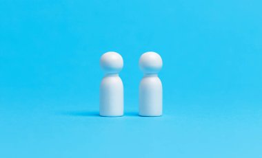 Sosyal mesafeli kavramsal görüntü. Beyaz ahşap figürler mavi arkaplanda mesafeyi koruyor