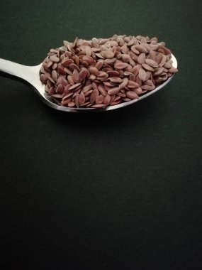 Siyah arka plan, vintage renk tonu üzerinde kaşık keten tohumu. Kopyalama alanı