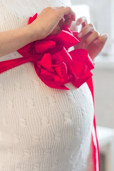 Elinde yay olan hamile bir kadının karnı.