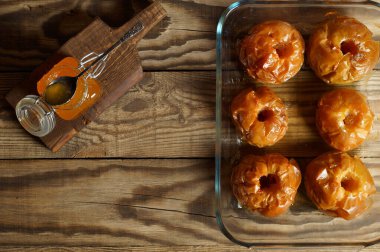Cam bir kasede fırınlanmış elmalar ve tahtanın üzerinde kaşıkla bir kavanoz bal..