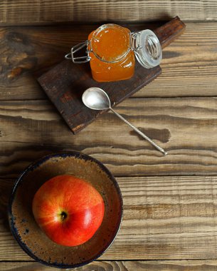 Kırmızı Elma tabakta ve bal kavanozu dokulu arka planda, üst manzara.