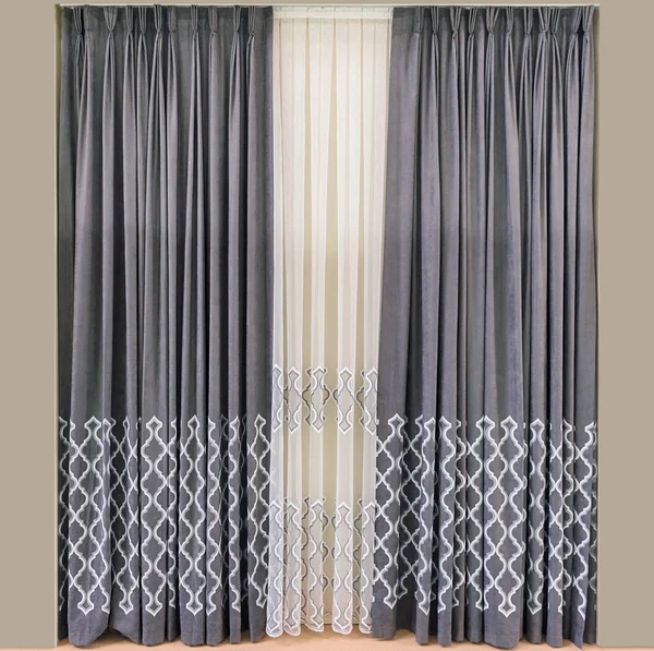 Modern interior design of the living room. Curtains made of natural gray fabric with embroidered geometric ornament, and tulle companion with the same pattern