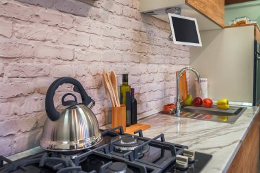 Mermer tezgah, tuğla önlük, çelik evye ve gaz sobası ile modern mutfak
