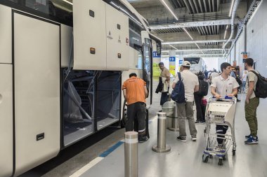 Türkiye. Istanbul. 5 Temmuz 2019. Yeni havaalanı. Terminalin alt katı. İnsanlar otobüsün bagaj bölmesine bagaj yüklerler.