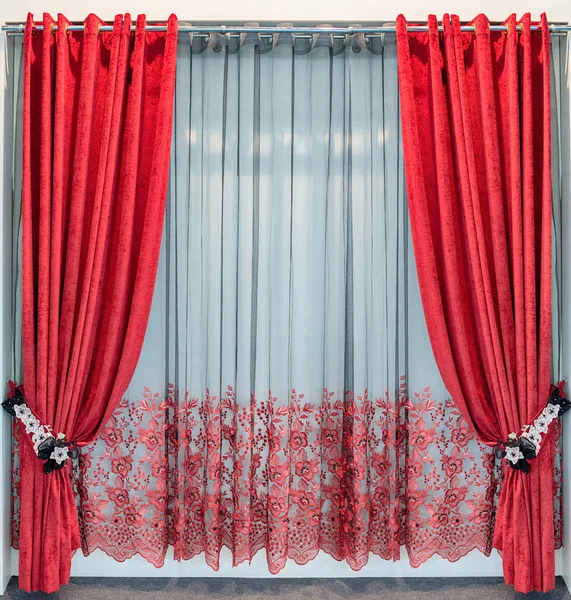 Красные бархатные занавески с ресницами на круглом металлическом карнизе, завязки из кружевных цветов и прозрачный тюль с вышивкой — стоковое фото