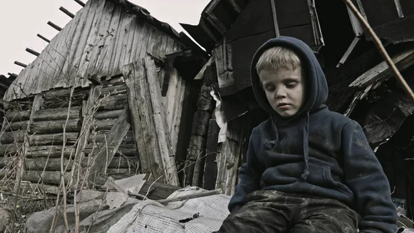 ちっちゃなホームレス孤児のそばに座っている放棄された建物 — ストック写真
