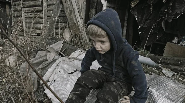 坐在废弃建筑旁的悲伤的小孤儿 — 图库照片