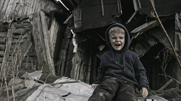 小无家可归的孤儿男孩哭在废弃的建筑物旁边 — 图库照片