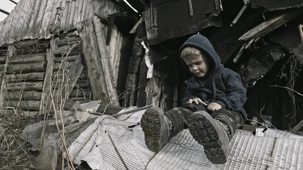 悲伤的无家可归的孤儿坐在和哭泣旁边建设在废弃的村庄 — 图库照片