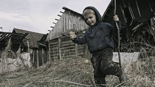 无家可归的白种人男孩玩枪在废弃的村庄 — 图库照片