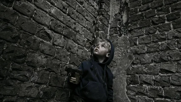 在废弃的建筑里拿着枪的无家可归的孤儿 — 图库照片