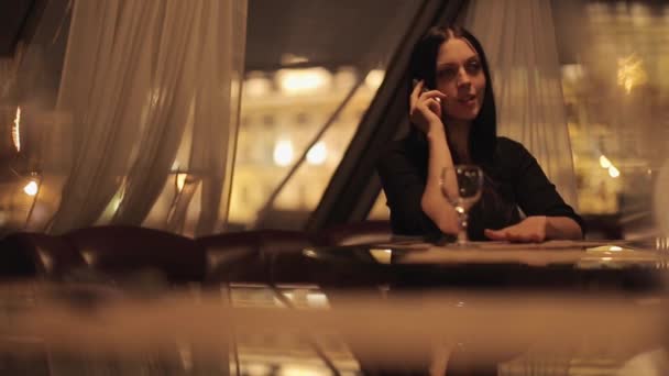 美しい若い女性レストランに座っていると 夜間のスマート フォンの話 — ストック動画