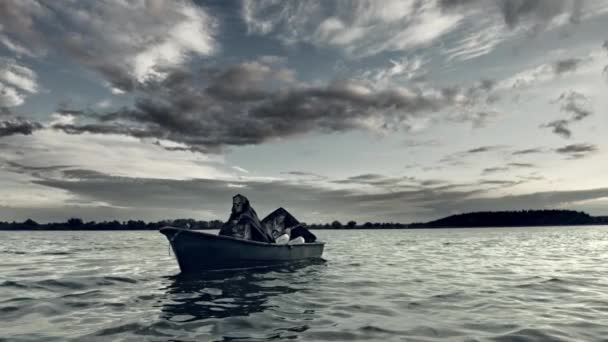 两个人戴着令人毛骨悚然的面具 漂浮在戏剧性的天空下的船 — 图库视频影像