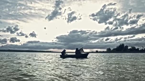不気味なマスクを着て 劇的な空の下でボートに浮かぶ2人 — ストック動画