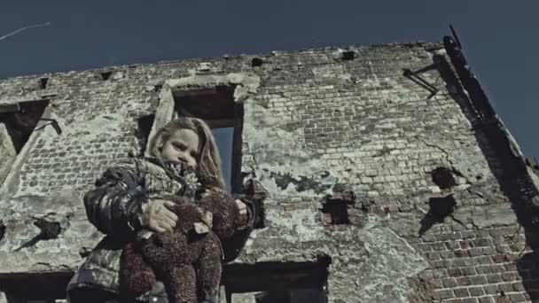 小肮脏的无家可归的女孩与熊玩具令人沮丧旁边废弃的建筑 — 图库视频影像