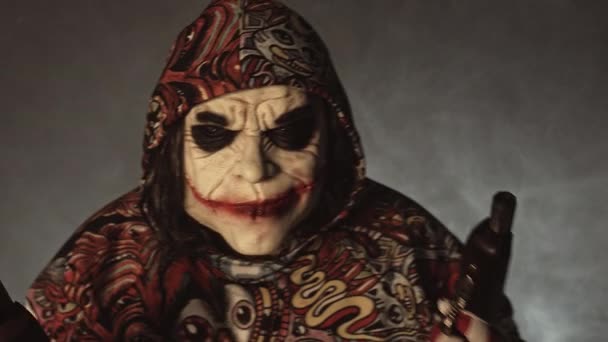 Gruseliger Clown Mit Kapuze Posiert Mit Waffen Vor Nebligem Hintergrund — Stockvideo