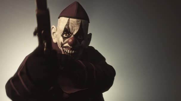 Темний Священик Страшній Масці Клоуна Позує Грошима Зброєю Сірому Фоні — стокове відео