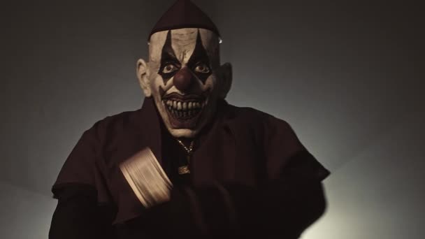 Mörka Präst Scary Clown Mask Poserar Med Pengar Och Pistol — Stockvideo