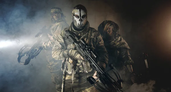 group of hunters in camouflage with modern weapons posing in dark building