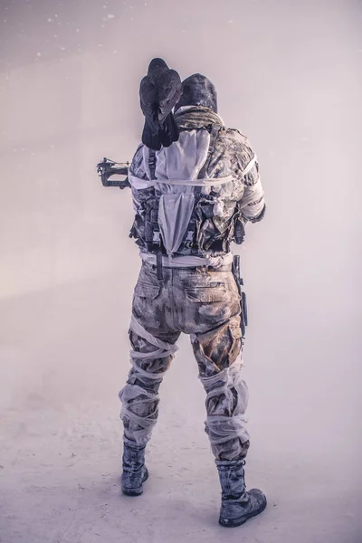 rear view of warrior man in mask with crossbow and raven posing against cold grey background