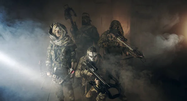 group of hunters in camouflage with modern weapons posing in dark building
