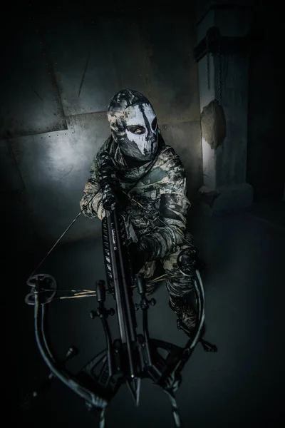 クロスボウ冷たい灰色の背景に対してポーズで仮面の戦士男 — ストック写真