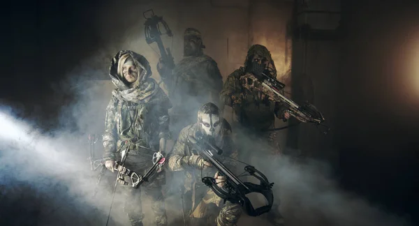 group of hunters in camouflage with modern weapons posing in dark building