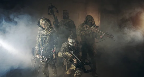 group of hunters in camouflage with modern weapons posing in dark building