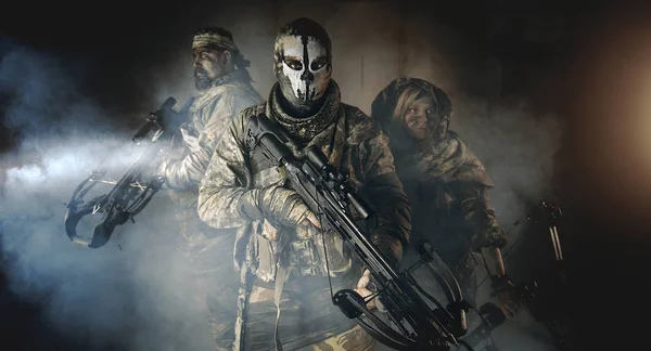 group of hunters in camouflage with modern weapons posing in dark building