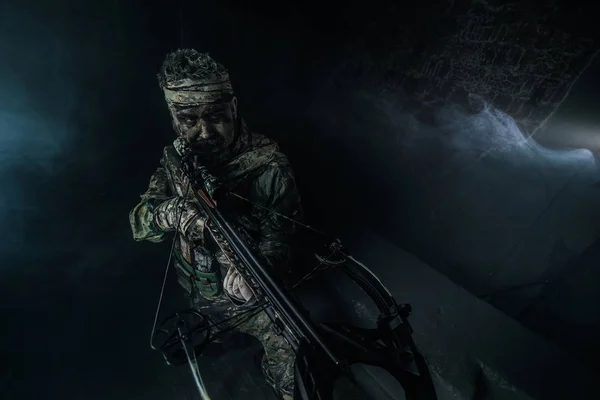 猎人男子在伪装与十字弓姿势对寒冷的灰色背景 — 图库照片
