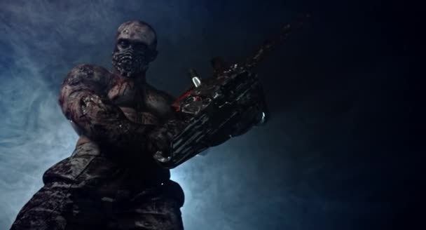 Griezelige Zombie Killer Met Chainsaw Poseren Tegen Mistige Donkere Achtergrond — Stockvideo