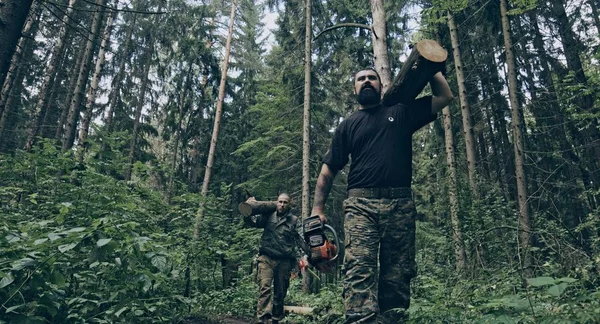 两个野蛮的高加索伐木工人拿着原木在森林里 — 图库照片