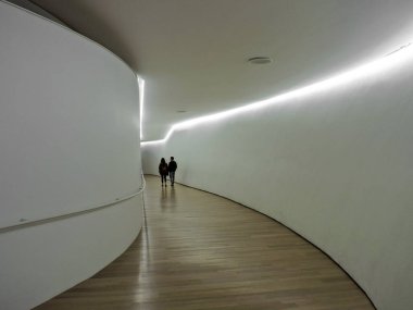 Ahşap zemin kaplama ve beyaz duvarlar ile bir iç koridorda yürüyen bir çift.