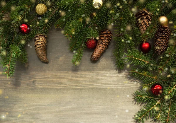 Yeni yıl süslemeleri, çam kozalakları ve ışık saçan ahşap arka planda fidan dallar. Yılbaşı afişi için tasarım ya da metin için yeri olan tebrik kartı.