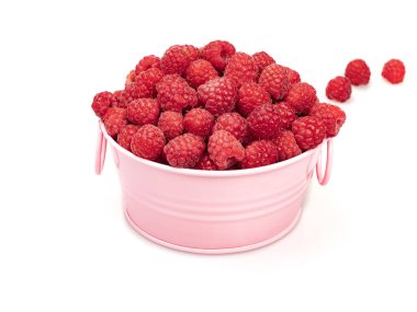 Olgun ahududu çilek pembe bir kase içinde ve arkasında dağınık, beyaz bir arka plan üzerinde. Close. Natürmort.