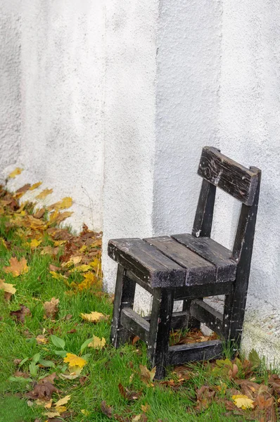 Lonely old chair against a white wall in the fall.