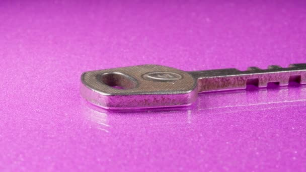 Sleutel op een roze achtergrond close-up. Zilvermetaal. — Stockvideo
