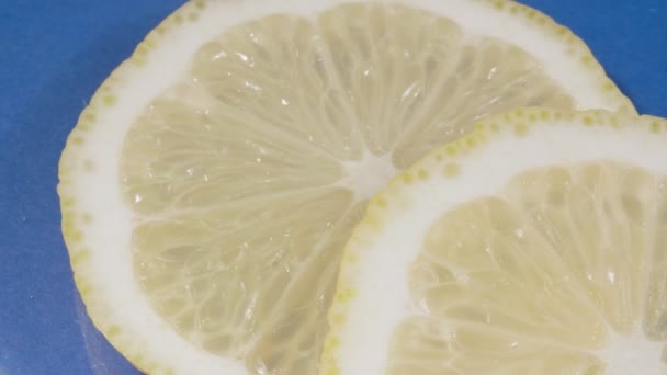 Zitronenscheiben aus nächster Nähe. Blauer Hintergrund. 4K-Video. Zitrusfrüchte. — Stockvideo